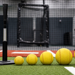 Several weighted softballs arranged from light to heavy beside a practice tee