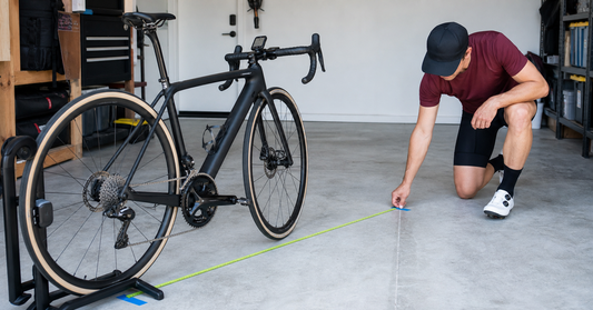 Cyclist measuring a bicycle wheel rollout beside a wireless bike computer and sensor
