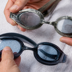 Used swim goggles being inspected for worn gaskets, strap damage, and cloudy lenses