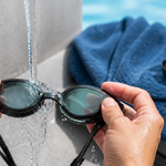 Swim goggles being gently rinsed with clean cool water after a pool session