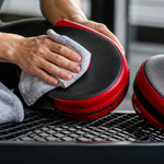 Boxing focus mitts being wiped clean with a soft cloth after practice