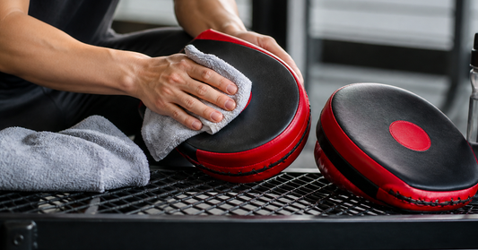 Boxing focus mitts being wiped clean with a soft cloth after practice