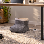 Electric foot warmer positioned under a clear home-office desk with controller and cord visible