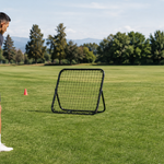 Athlete checking the angle and clear return path of a small rebounder net on grass
